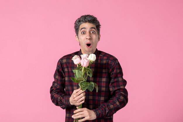 Front view young male holding beautiful pink roses on pink wall