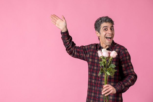 Front view young male holding beautiful pink roses on pink wall