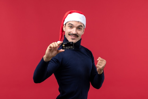 Front view young male holding black bank card on red background