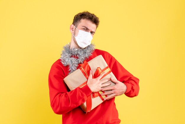 Front view young male holding christmas present in mask