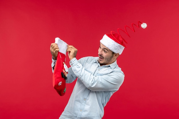 Вид спереди молодой мужчина держит рождественский носок, праздник Рождества