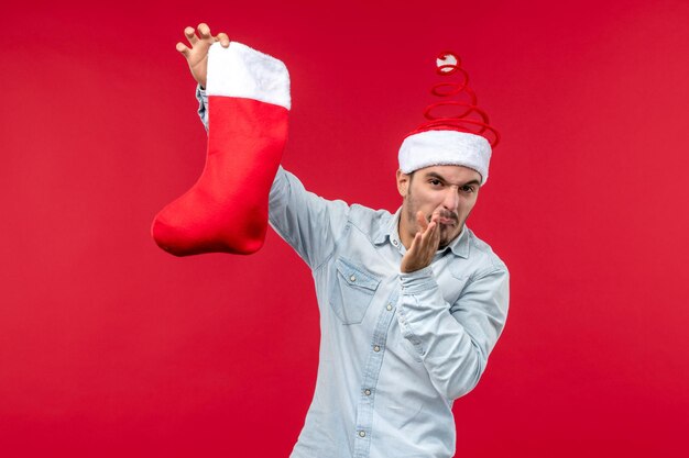 Free photo front view young male holding christmas sock, christmas holidays christmas