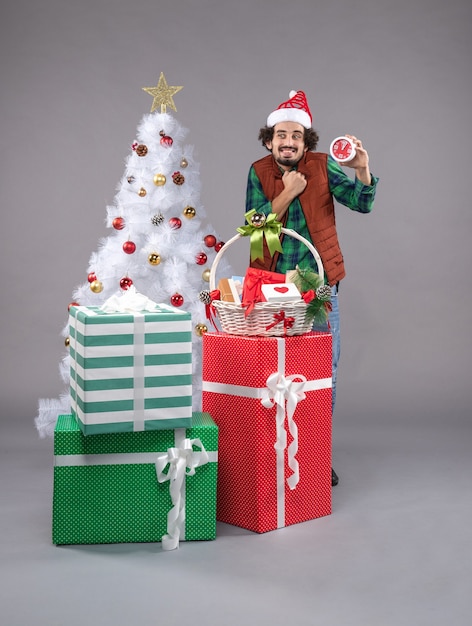 Front view young male holding clock around presents on a grey