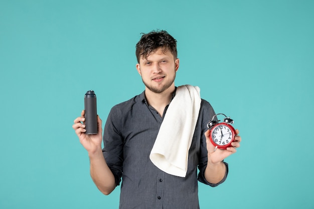 front view young male holding a clock on blue background