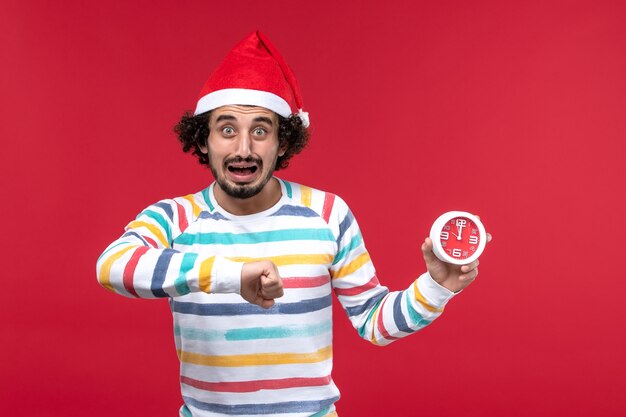 Front view young male holding clocks on red wall red new year male holidays