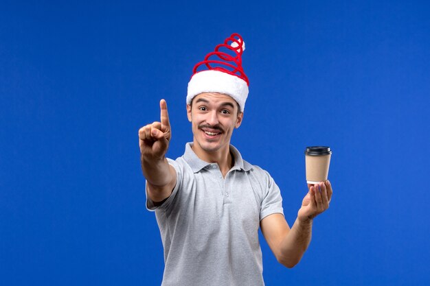 Front view young male holding coffee cup on blue desk new year male holiday emotions