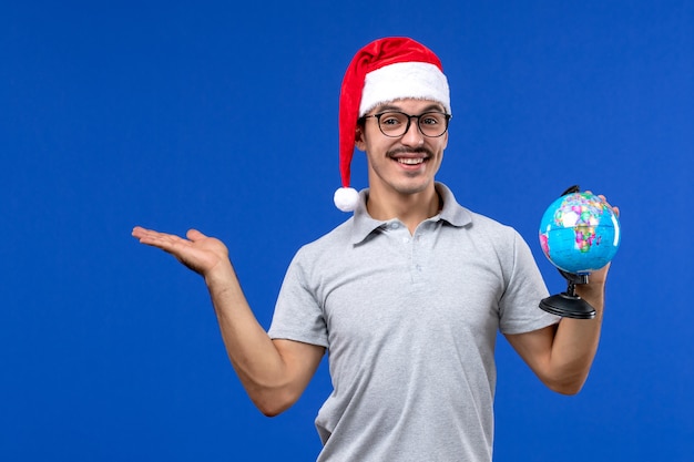 Front view young male holding earth globe on blue wall plane human vacation trip