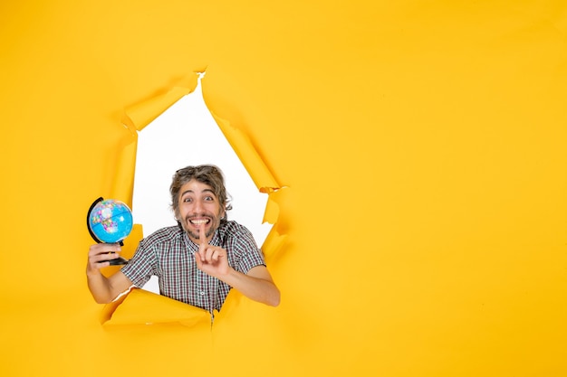 Front view young male holding earth globe on the yellow background emotion planet christmas holiday country world color