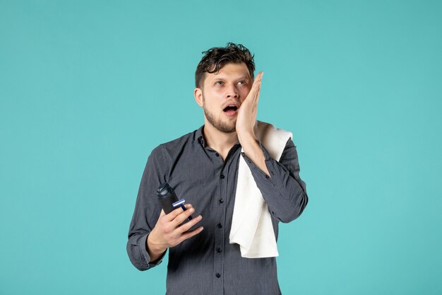 front view young male holding foam for shaving and razor on blue background