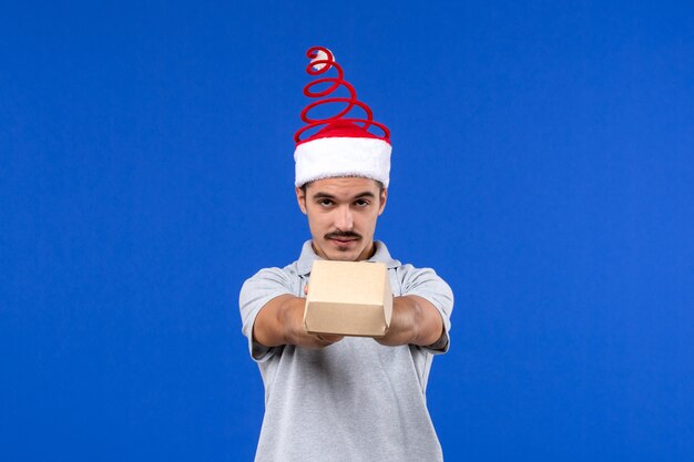 Front view young male holding food package on blue wall male job food service human