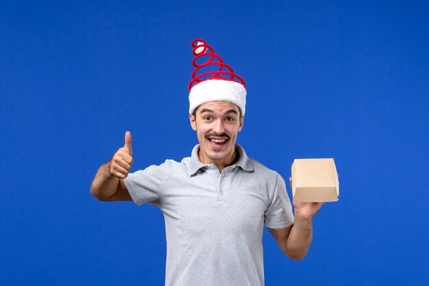 Front view young male holding food package on light blue wall food male service job