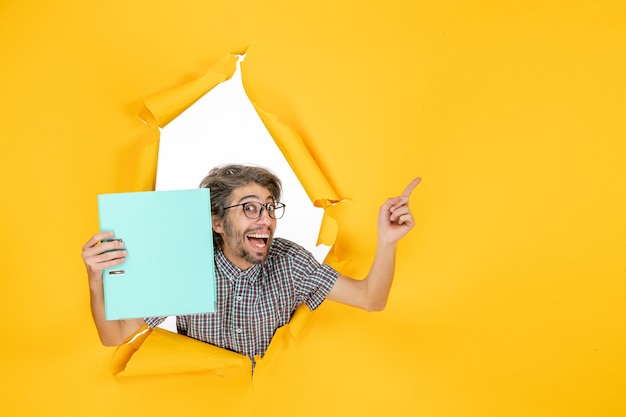 Front view young male holding green file on yellow background color job new year office emotion work holiday