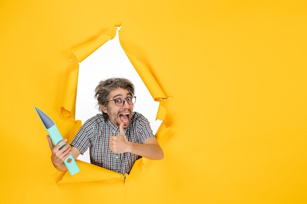 Free photo front view of young male holding green file on yellow wall