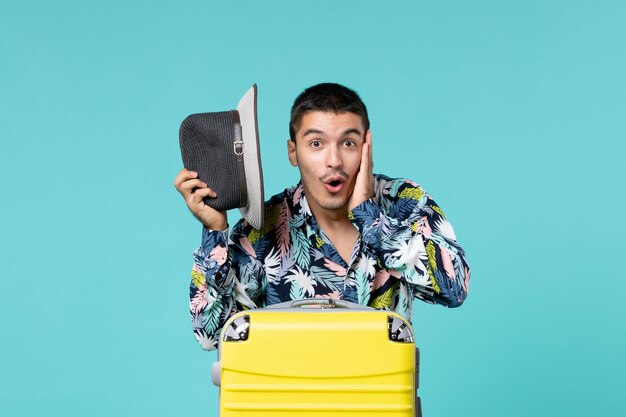 Front view young male holding his hat and preparing for trip on a blue space