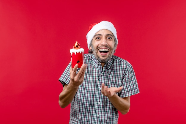 Front view of young male holding little holiday toy on red