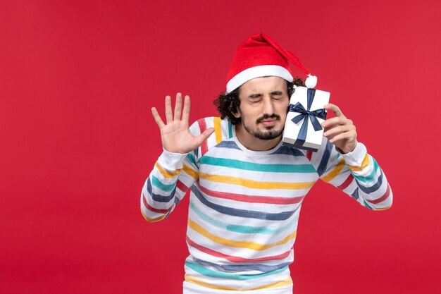 Front view young male holding little present on red floor red emotion holiday new year