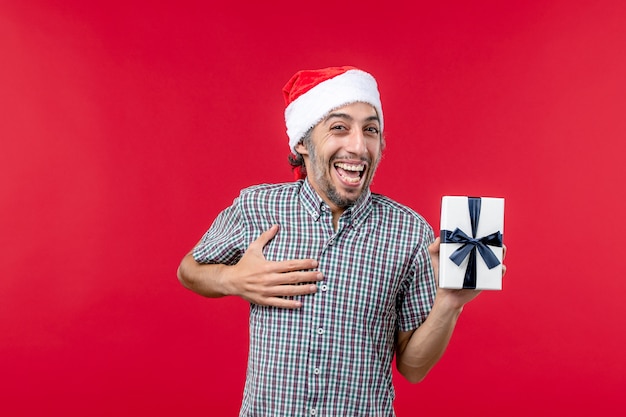 Front view of young male holding little present on red