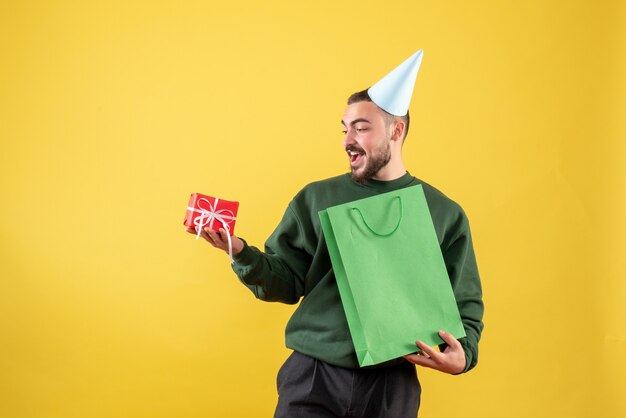 Front view young male holding little present on yellow background