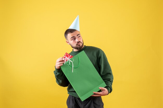 Front view young male holding little present on yellow background