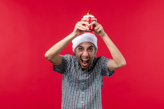 Front view of young male holding little toy on red