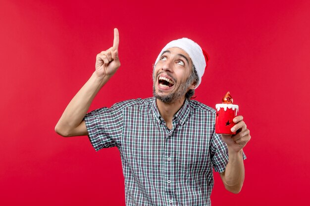 Front view of young male holding little toy on red