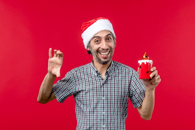 Front view of young male holding little toy on red