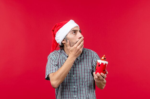 Front view of young male holding little toy on red