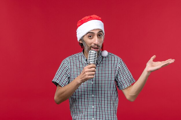 Front view young male holding mic on red floor emotion male model singer