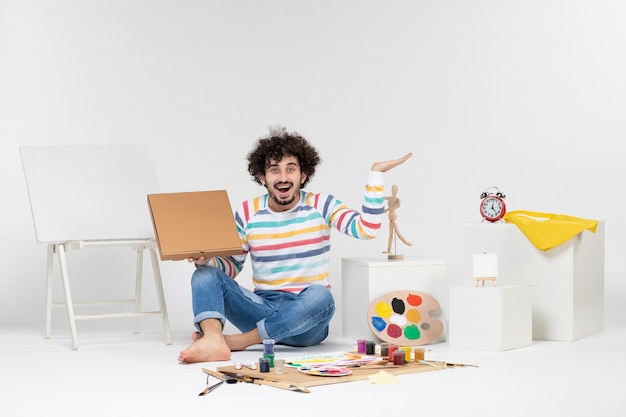 Free photo front view of young male holding pizza box on white wall