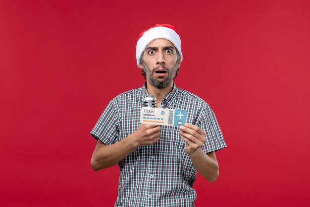 Front view young male holding plane ticket and mic on red background