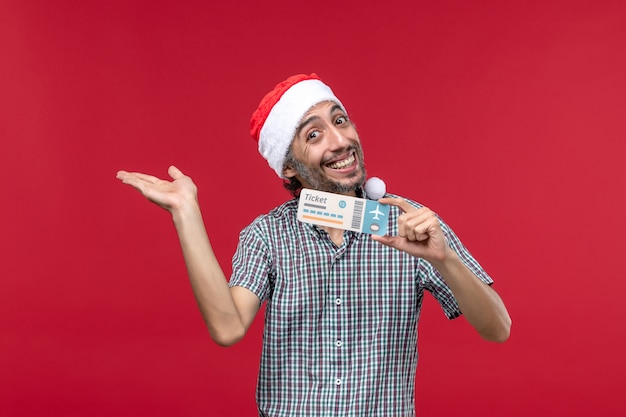 Front view young male holding plane ticket on a red background
