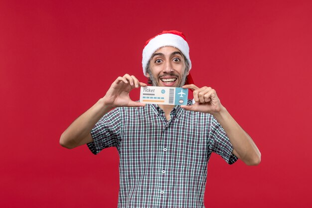 Front view young male holding plane ticket on red background