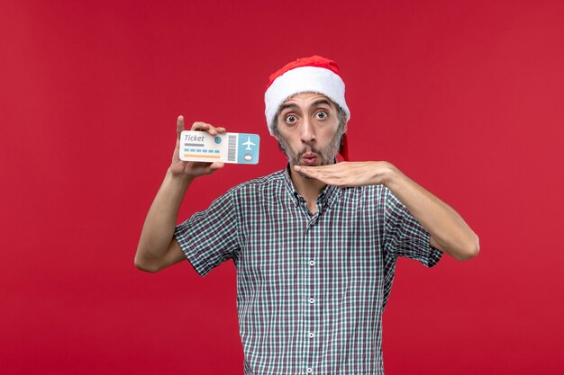 Front view young male holding plane ticket on red background