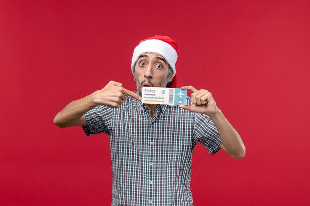 Front view young male holding plane ticket on red background