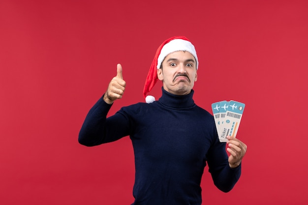 Front view young male holding plane tickets on light red background