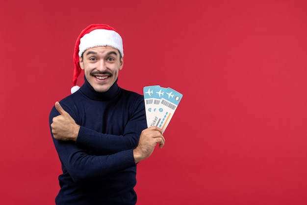 Front view young male holding plane tickets on a red background