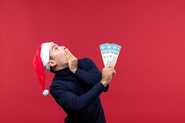 Front view young male holding plane tickets on a red background