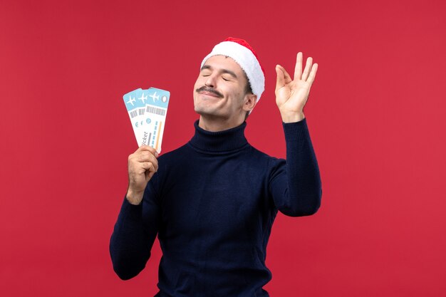 Front view young male holding plane tickets on a red background