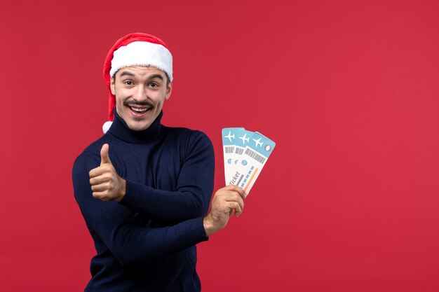 Front view young male holding plane tickets on red background