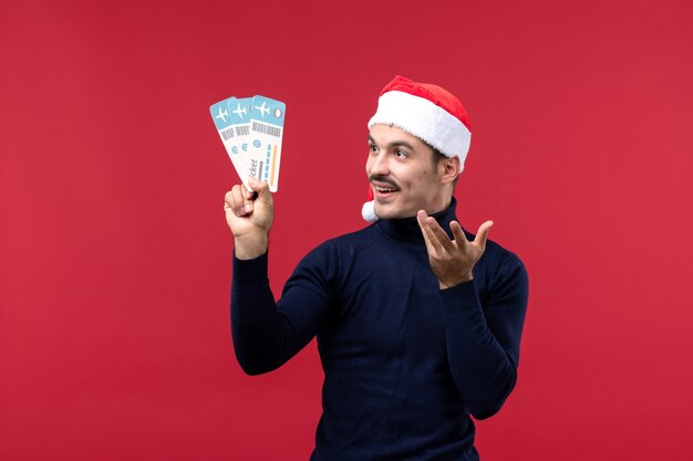 Front view young male holding plane tickets on red background