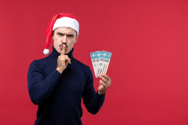 Front view young male holding plane tickets on red background