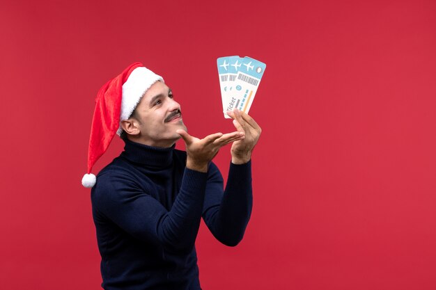 Front view young male holding plane tickets on red background