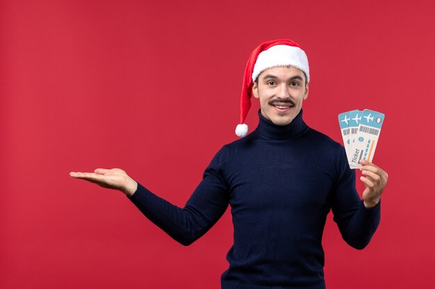 Front view young male holding plane tickets on red background