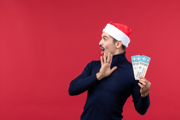 Front view young male holding plane tickets on red background