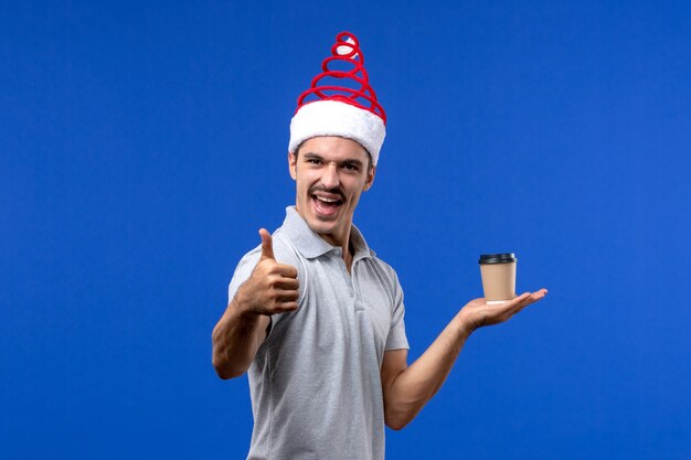 Front view young male holding plastic coffee cup on blue desk holiday male new year