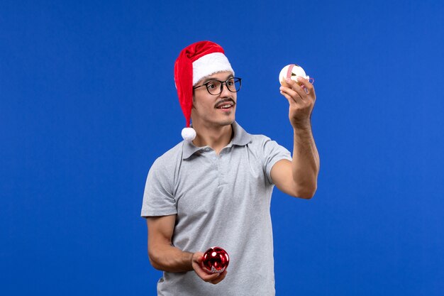 Front view young male holding plastic tree toys on blue background human male holiday new year