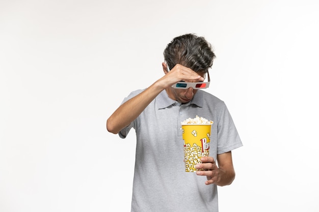 Foto gratuita vista frontale giovane maschio che tiene popcorn in occhiali da sole d su superficie bianca