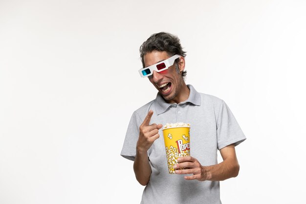 Front view young male holding popcorn package in d sunglasses on a white surface