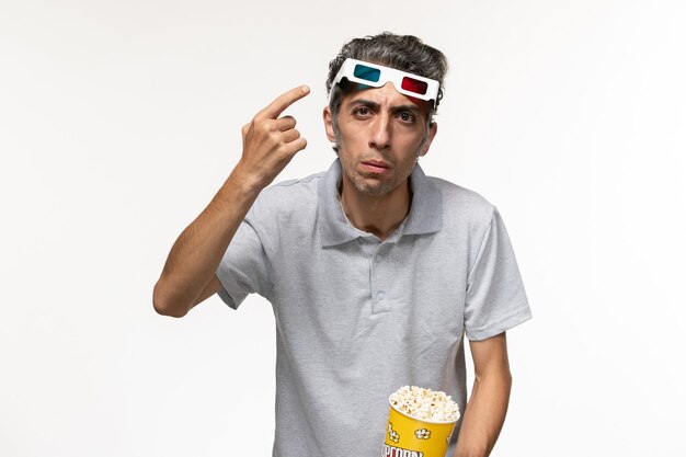 Front view young male holding popcorn package and wearing d sunglasses on white surface