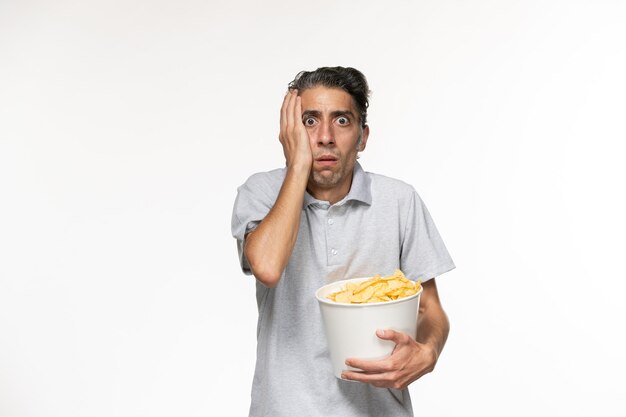 Front view young male holding potato chips and watching movie on white surface